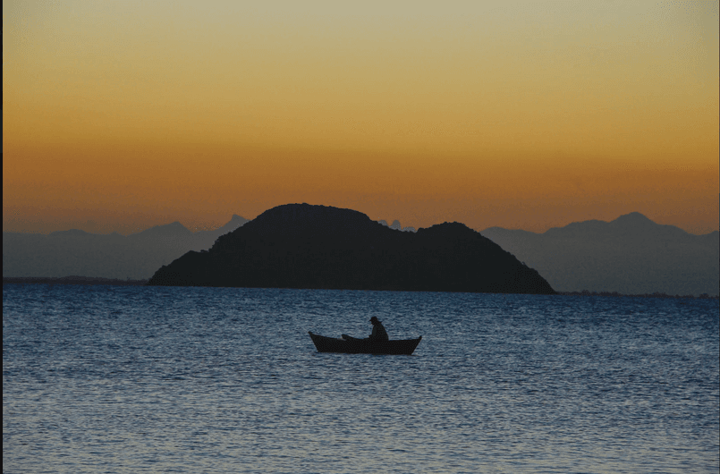 Pescador em silhueta ao pôr do sol